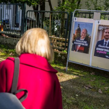 Toulouse, 20 mars 2026. Une personne regarde les panneaux électoraux en vue du second tour des élections municipales le 22 mars 2026 avec l’actuel Maire de Toulouse Jean Luc Moudenc (G) et Francois Piquemal pour LFI (D). Photo : Frédéric Scheiber / Hans Lucas via AFP