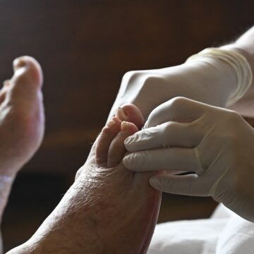 Une aide-soignante soigne le pied d’une personne âgée lors d’une visite à domicile, reflet du besoin croissant de soutien médical à domicile pour les personnes agées. Paris. 17 octobre 2025. Photo : Eric Beracassat / Hans Lucas via AFP
